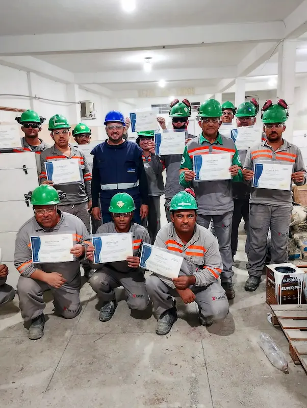 Turma de pedreiros com os certificados após a conclusão do programa de aperfeiçoamento